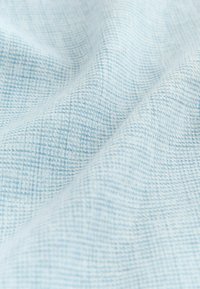 Jasnoniebieska tkanina o plecionej fakturze z wzorem w kratkę. Powierzchnia wykazuje subtelne zróżnicowanie odcieni i gęstości splotu.