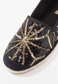Czarne espadryle z cekinowym wzorem w złote i srebrne motywy. Naturalna podeszwa z juty i czarna tkanina wewnętrzna.