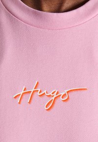 Roze katoenen t-shirt met een ronde hals en een wit geborduurd "Hugo" logo in het midden. Glad textuur met een aansluitende pasvorm.
