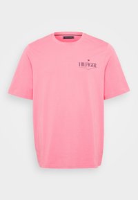 Pink short-sleeve T-shirt made of cotton; features a logo in dark navy script on the left chest area; classic crew neckline.
