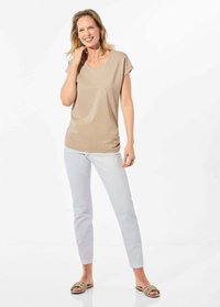 Tanshort-sleeve top met een ronde hals, gecombineerd met lichtblauwe, aansluitende broek en beige sandalen, staand tegen een witte achtergrond.