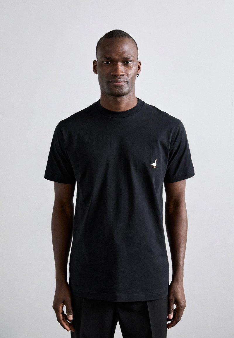 Meeste must puuvillane T-särk ümmarguse kaelusega, millel on vasakul rinnal väike valge lindude logo. Lühikesed varrukad, vabalt lahtine mudel.