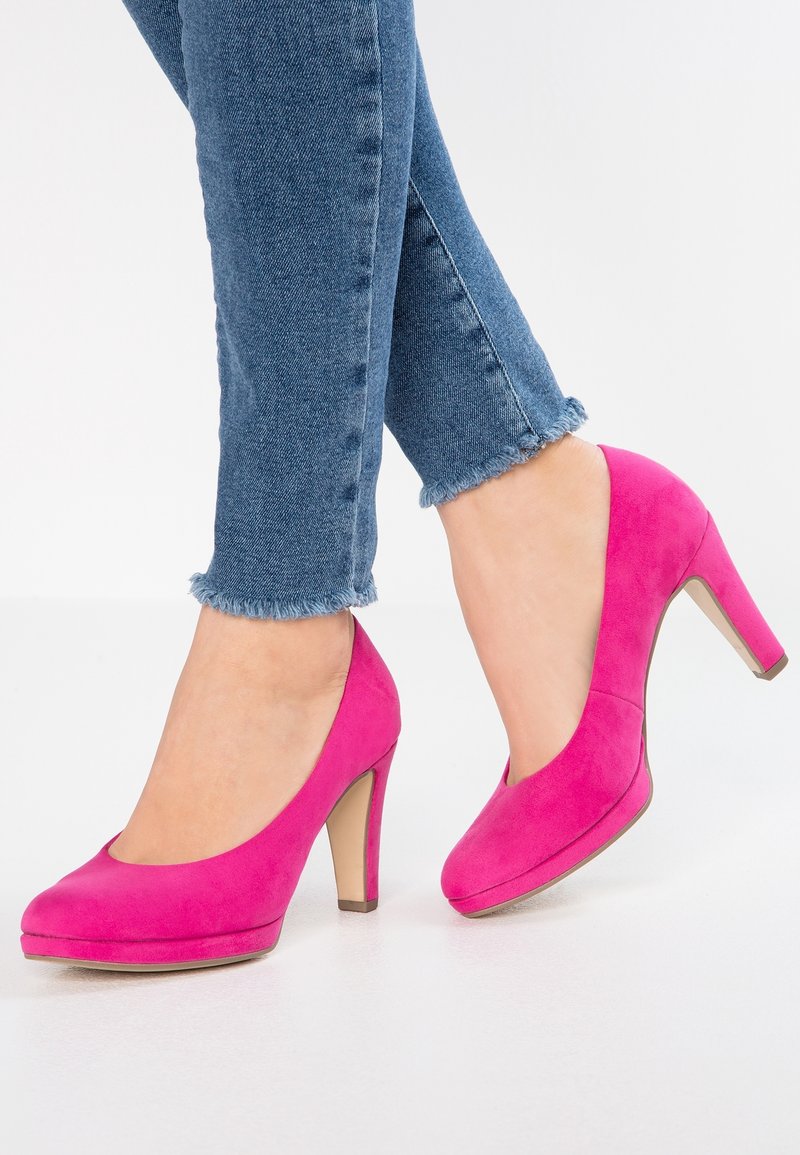 Chaussures à talons hauts en daim rose avec un bout arrondi et un talon de 10 cm, associées à un jean court en denim avec des détails d'ourlet effiloché.
