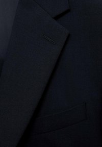 Mørkeblå skræddersyet blazer med struktureret revers, subtil tekstur og en enkelt lomme; designet i letvægtsstof til formelt tøj.
