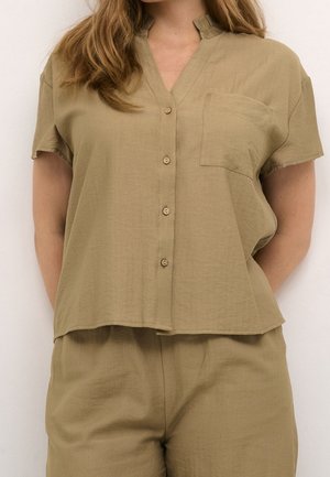 Blusa khaki a maniche corte con scollo a V, chiusura frontale con cinque bottoni e taschino. Tessuto leggero e testurizzato con una vestibilità rilassata.