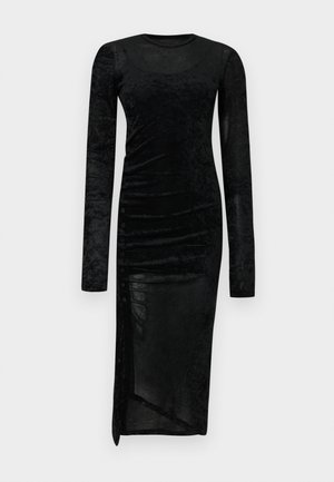 Dolga črna sametasta obleka z dolgemi rokavi, ki ima prilegajočo silhueto, nagubane stranske detajle in razporek na robu. Vsebuje gumbe kot okras na eni strani.