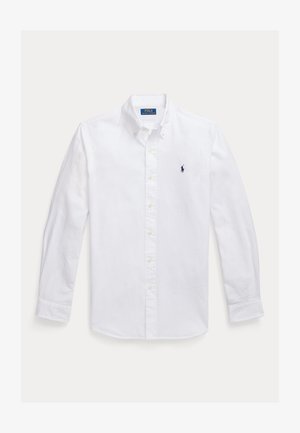 Camasa alba cu maneci lungi si nasturi, guler ascutit, cu un logo mic navy pe pieptul stang si nasturi galbeni. Textura neteda a tesaturii.