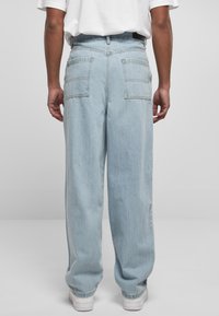 Ljusblå denimjeans med lös passform, utrustade med två bakfickor och synlig sömnad. Slutet är något avsmalnat vid vristerna.