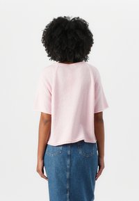 Lys rosa kortermet topp i teksturert stoff, med rund hals og litt cropped søm, kombinert med et denimskjørt.