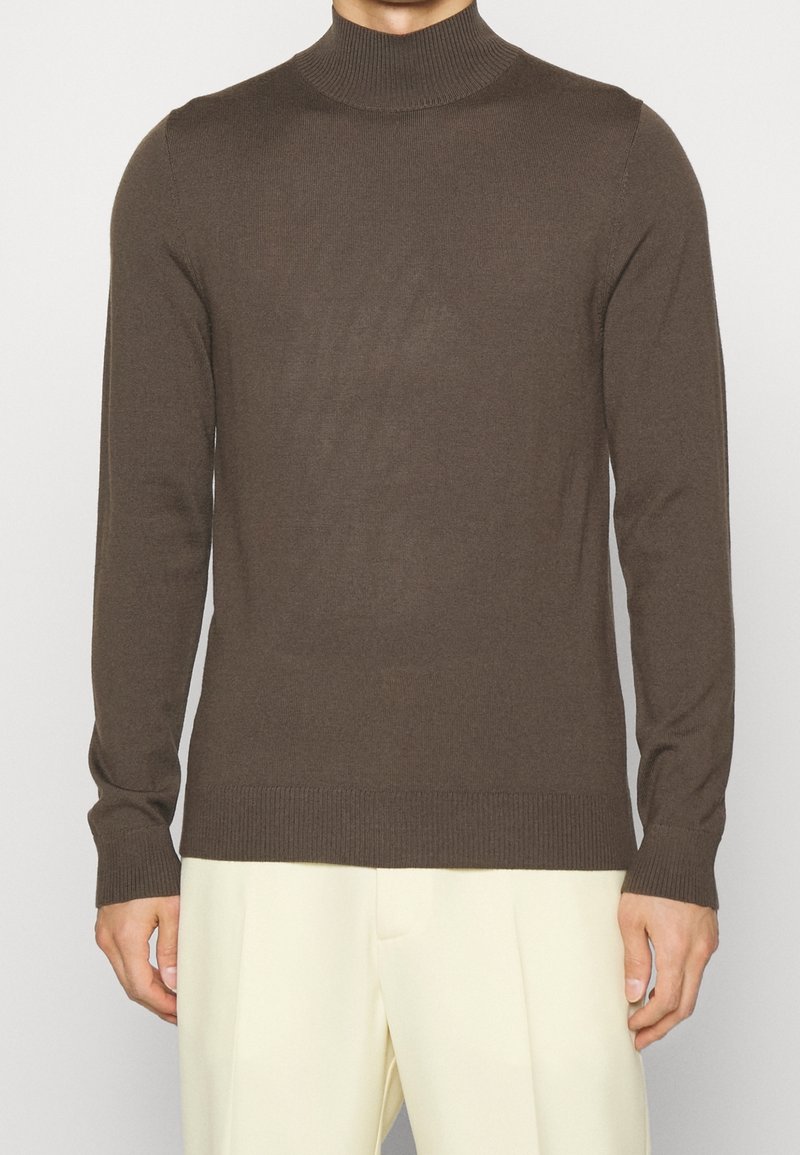 Pull à col roulé marron en tissu tricoté doux. Dispose de manches longues, de poignets côtelés et d'un ourlet côtelé pour un look ajusté.