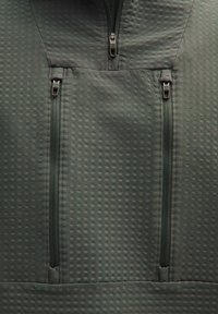 Fleece pullover in donkergroen met een gestructureerd oppervlak, twee ritszakken op de borst en een hoge kraag met een rits van de voorkant tot de helft.