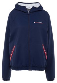 Marinblå zip-jacka med huva, elastiska ärmslut och nederkant. Har röda och vita ränder längs sidorna och en liten logotyp på bröstet.