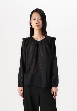 Blusa nera con un motivo testurizzato di piccoli rettangoli, dotata di maniche arricciate e scollatura rotonda, abbinata a pantaloni neri.