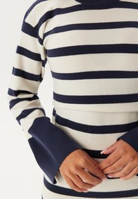Gestreifter Strickpullover in Creme und Marineblau. Mit langen Ärmeln und breiten Bündchen, einem figurbetonten Design und einem gerippten Textur.