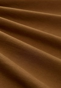 Bruine stof met een gladde textuur, gekenmerkt door zachte plooien en een consistente kleur door het geheel. Ideaal voor verschillende textieltoepassingen.