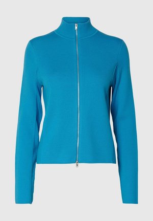 Veste tricotée bleu à manches longues avec un col montant et une fermeture éclair argentée intégrale à l'avant, présentée sur un fond uni.