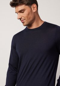 Navy blue, long-sleeve, crew-neck sweater with a smooth texture, fitted design, and minimal seams, showcasing a simple and clean aesthetic.