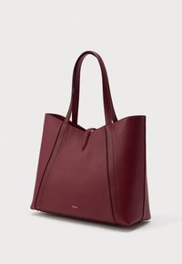 Bordová kožená taška s dvoma rukoväťami, minimalistický dizajn a malé zlaté logo "Furla" na prednej strane, fotografovaná na bielom pozadí.