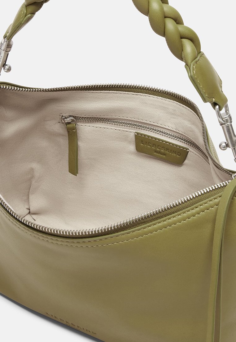 Helles grünes Lederhandtasche mit geflochtenem Riemen, offener Oberreißverschluss und beigem Innenfutter aus Stoff mit einer kleinen Reißverschlusstasche.