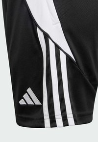 Melnas sporta šortus, kas izgatavoti no gludas auduma, ar baltām sānu svītrām un izšūtu pelēku Adidas logo apakšmalā.