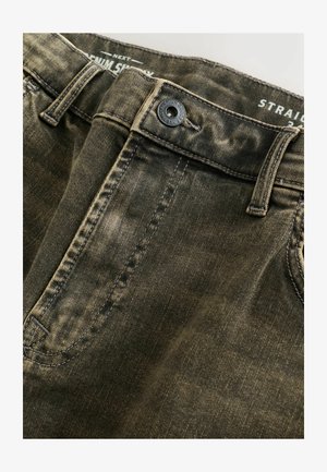 Tamsiai žali džinsai iš džinso audinio su tiesiu kirpimu, metaline sagos užsegimu ir kontrastingomis siūlėmis. Audinys turi tekstūrą su nudėvėtais akcentais.