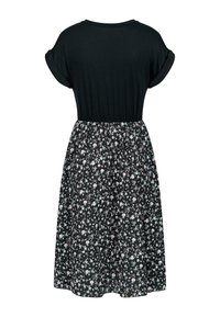 Vestito nero con una parte superiore ampia e maniche arrotolate, con una vita che si trasforma in una gonna a fiori con piccoli fiori bianchi e blu.
