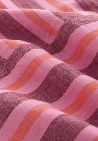 Tissu à rayures ondulées dans des nuances de rose, violet et orange, montrant une texture détaillée et des coutures sur des plis de matière douce.