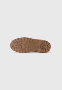 Suela de zapato de goma en color marrón, con un patrón de agarre texturizado que presenta elementos en zigzag y acentos elevados para mejorar la tracción y la durabilidad.