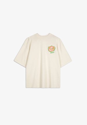 Camiseta de algodón color crema con un gráfico de rosa colorido en el lado izquierdo del pecho. Mangas cortas, corte holgado, escote redondo, textura suave.
