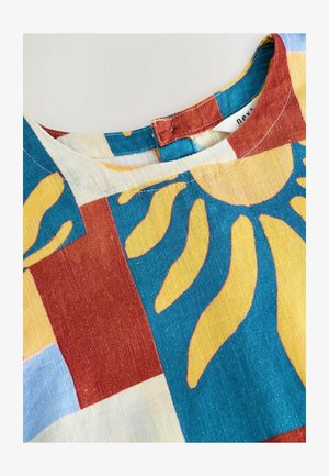 Colorful cotton blouse featuring a round neckline, with a patchwork pattern of blue, red, and yellow leaf motifs on a light background.