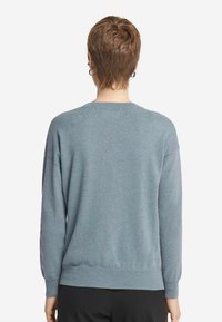 Niebieski sweter z miękkiego materiału, z okrągłym dekoltem, długimi rękawami i prążkowanym wykończeniem. Gładka tekstura, luźny krój.