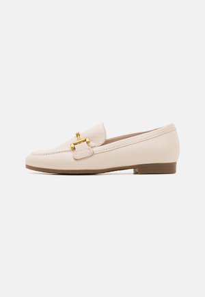 Beige leather loafer with a soft texture, a rounded toe, decorative strap with gold hardware, and a low, brown heel.