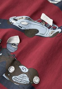 La tela presenta coches de dibujos animados sobre un fondo burdeos, destacando un coche azul claro y un coche marrón con detalles y patrones distintivos.