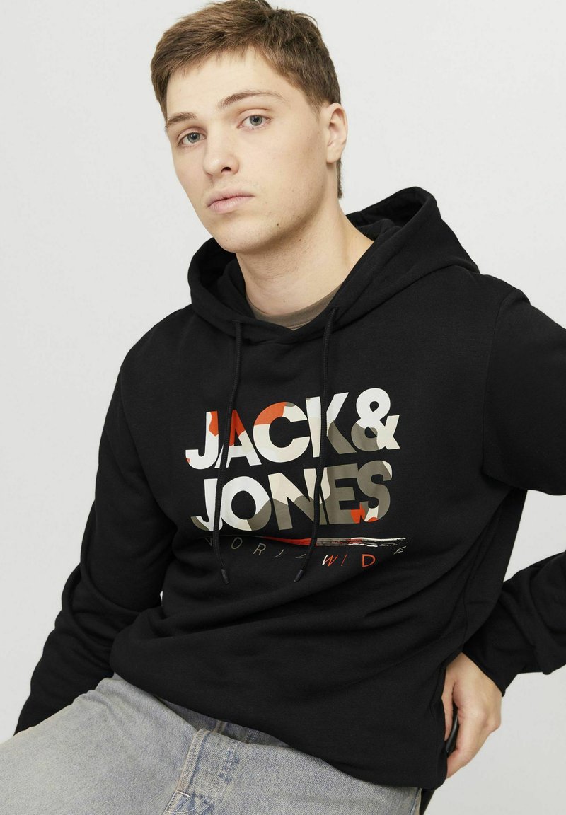 Felpa nera con una grande stampa grafica in grigio, bianco e rosso. Presenta un cappuccio con cordino e un tessuto morbido e textured.