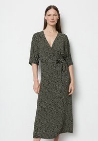 Robe portefeuille à motif noir et crème avec un décolleté en V profond, des manches courtes et une ceinture sur le côté, présentant une coupe midi fluide.