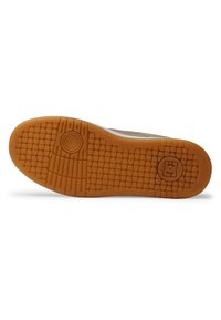 Semelle en caoutchouc avec un motif de grip texturé, comportant un accent circulaire et un logo. La couleur est brune avec un détail supérieur gris clair.