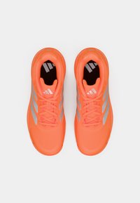 Φωτεινά πορτοκαλί αθλητικά παπούτσια με γκρι ρίγες, δεμένα κορδόνια, εμφανίζονται από πάνω σε λευκό φόντο.