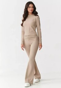 Beżowy, prążkowany top z długim rękawem o dopasowanym kroju, w połączeniu z pasującymi spodniami typu dzwony. Miękka, gładka tkanina o subtelnej fakturze i bocznych marszczeniach.