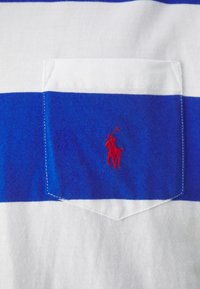 Vit och blårandig polo skjorta med en liten röd broderad hästlogotyp på vänster ficka. Tillverkad av mjukt bomullstyg.