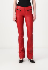 Red leather flared pants with textured surface, two zippered pockets, and a fitted waist. Worn with black high-heeled shoes.