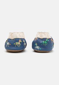Des chaussures en cuir bleu ornées de motifs animaliers colorés, avec un poignet élastique beige clair et une semelle marron texturée.