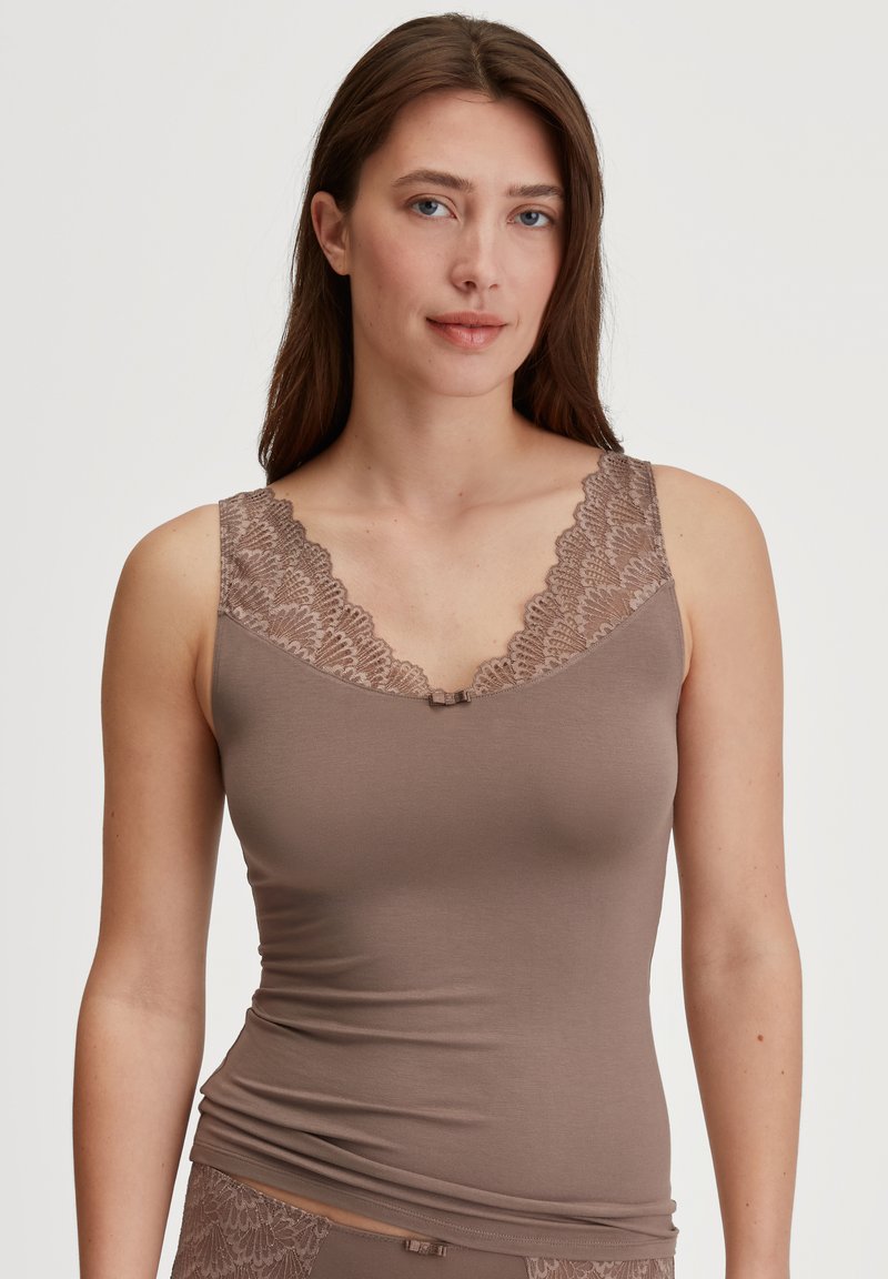 Top canna marrone con bordo in pizzo e un piccolo gancio centrale. Presenta un collo a giro e una silhouette aderente. Tessuto morbido e liscio.