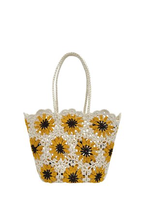 Sac cabas au crochet avec des motifs de tournesol jaunes et noirs sur un fond blanc en maille ouverte et des anses tressées.