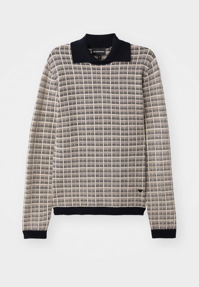 Pullover de malha em bege com um padrão de quadrados e gola azul-marinho. Apresenta mangas longas e punhos azul-marinho, destacando o tecido texturizado.