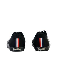 Zapatillas de ante negras con una franja trasera en rojo, blanco y azul, con una suela texturizada y la marca "Redskins" en blanco.