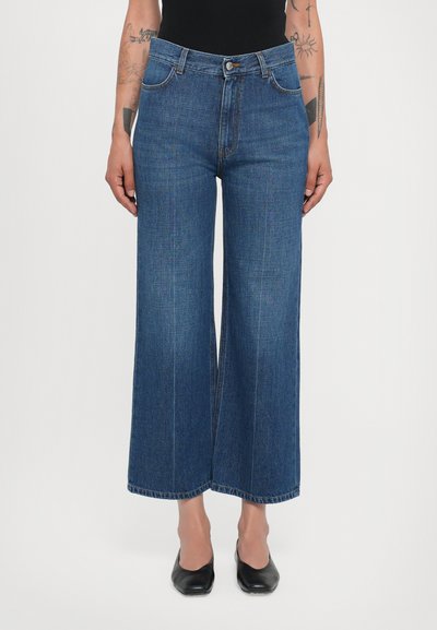 Brede jeans in donkerblauwe denim, hoog in de taille, met voorzakken en een rechte snit. Zichtbare stiksels langs de naden en de zoom.