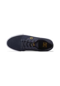 Navy blue suede sneaker with a white rubber sole, featuring yellow logo detail and standard lace-up design. Smooth texture overall.