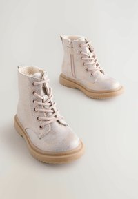 Ljust rosa, texturerade ankelstövlar med en glänsande yta. Har snörning, en dragkedja och en mjuk imitation av päls inuti. Gummisulor för bra grepp.