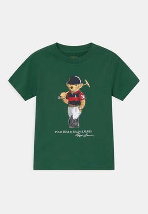 Chemise verte à manches courtes avec un graphisme d'un ours habillé en joueur de polo tenant un maillet et texte "Polo Bear by Ralph Lauren."