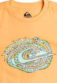Oranžové bavlněné tričko s kruhovou grafikou se vzorem hada, modrými a zelenými akcenty a textem "Quiksilver" ve vlnkovém písmu.